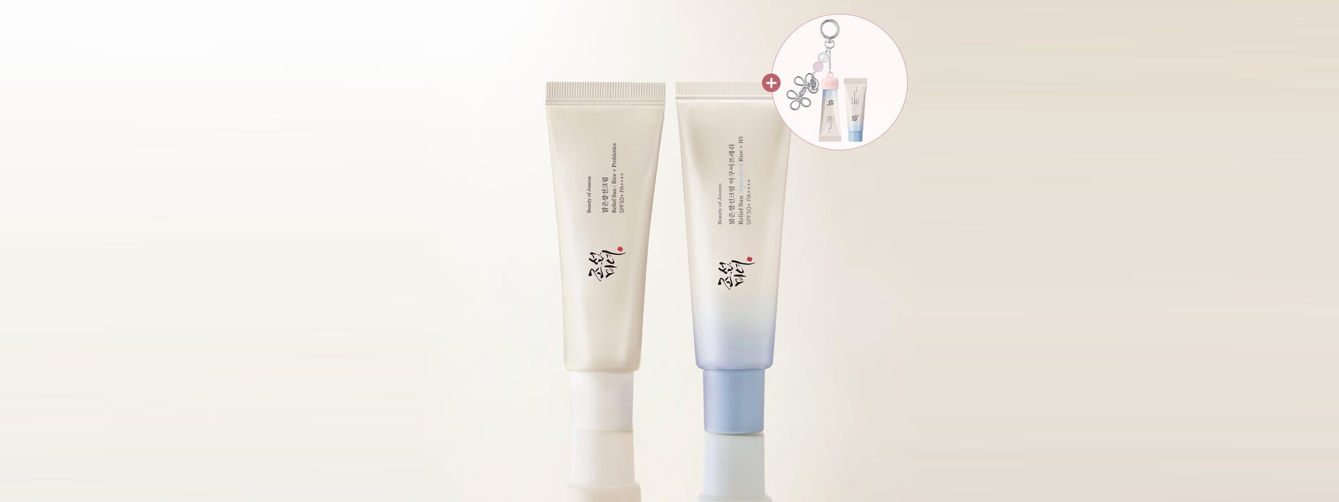 Two cosmetic tubes standing upright on a reflective surface against a plain light background, with a small circular inset showing an additional item.