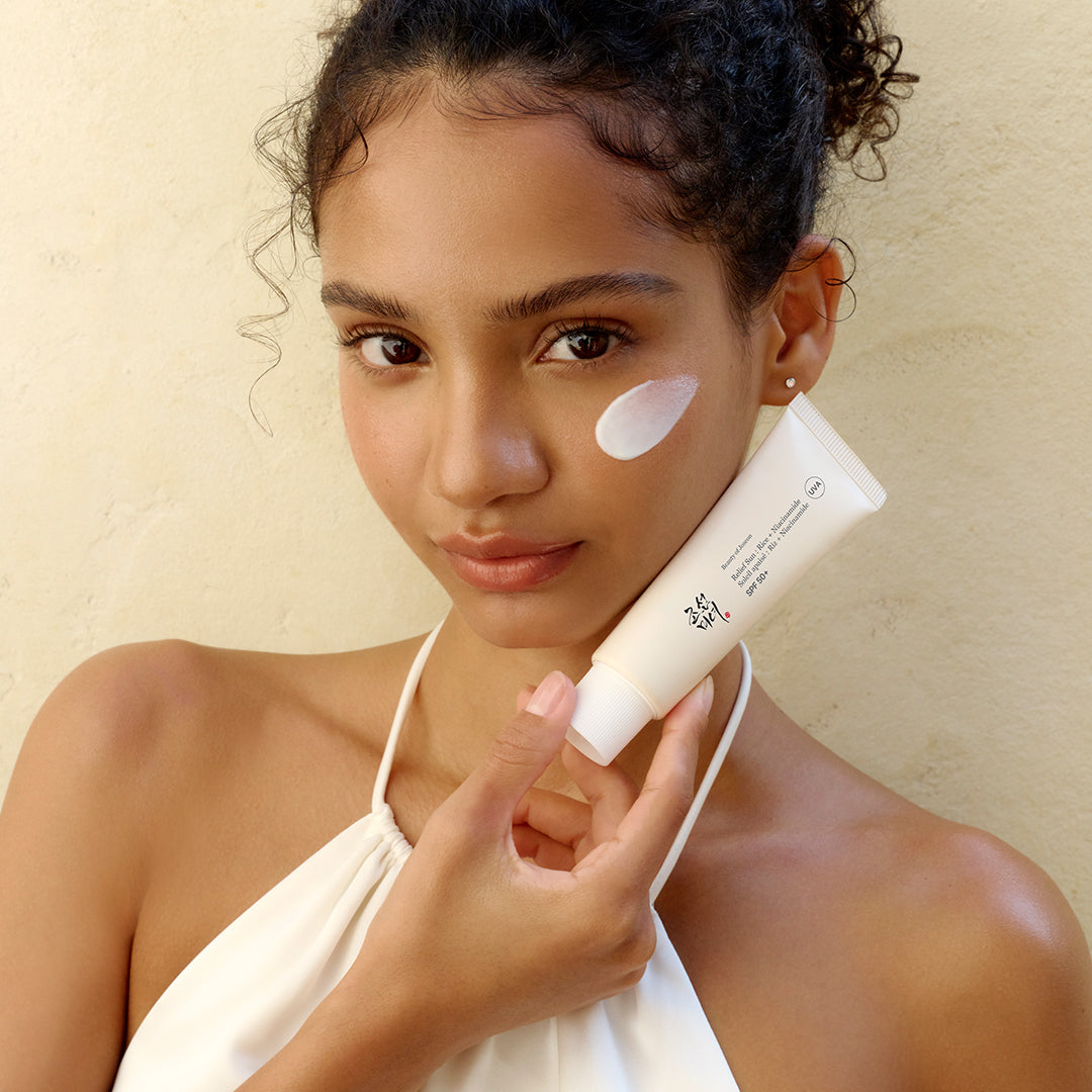 a woman holding a tube of cream on her face